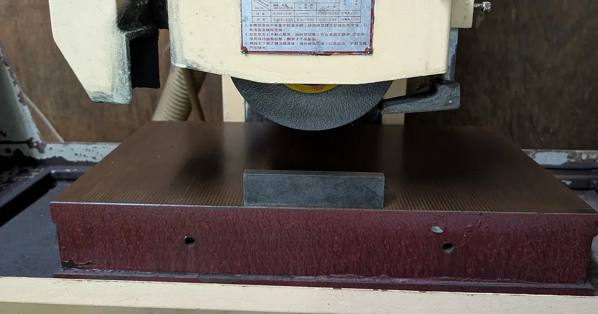 Grinding wheel above a workpiece on the cast table of a surface grinding machine, a grinding machine base
